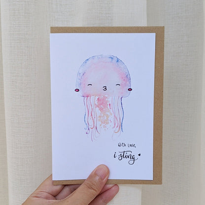 Greeting card of with watercolour illustration of a jellyfish kissing, signed off "with love, I sting" being held by a hand
