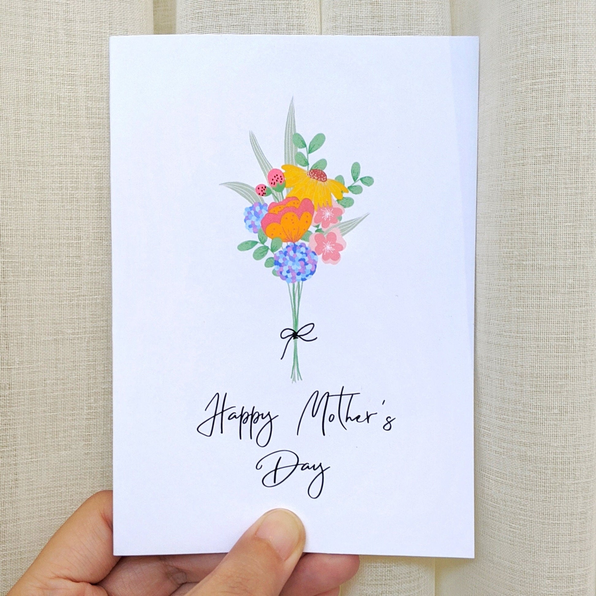 Greeting card held by hand with illustration of a colourful flower bouquet and lettering "Happy Mother's Day"