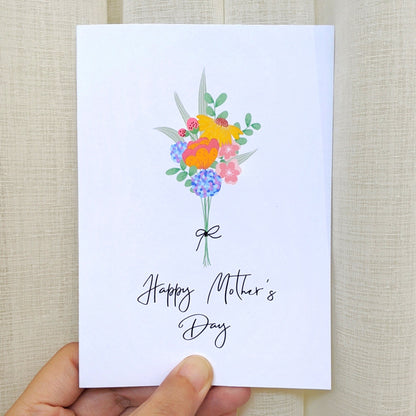 Greeting card held by hand with illustration of a colourful flower bouquet and lettering "Happy Mother's Day"