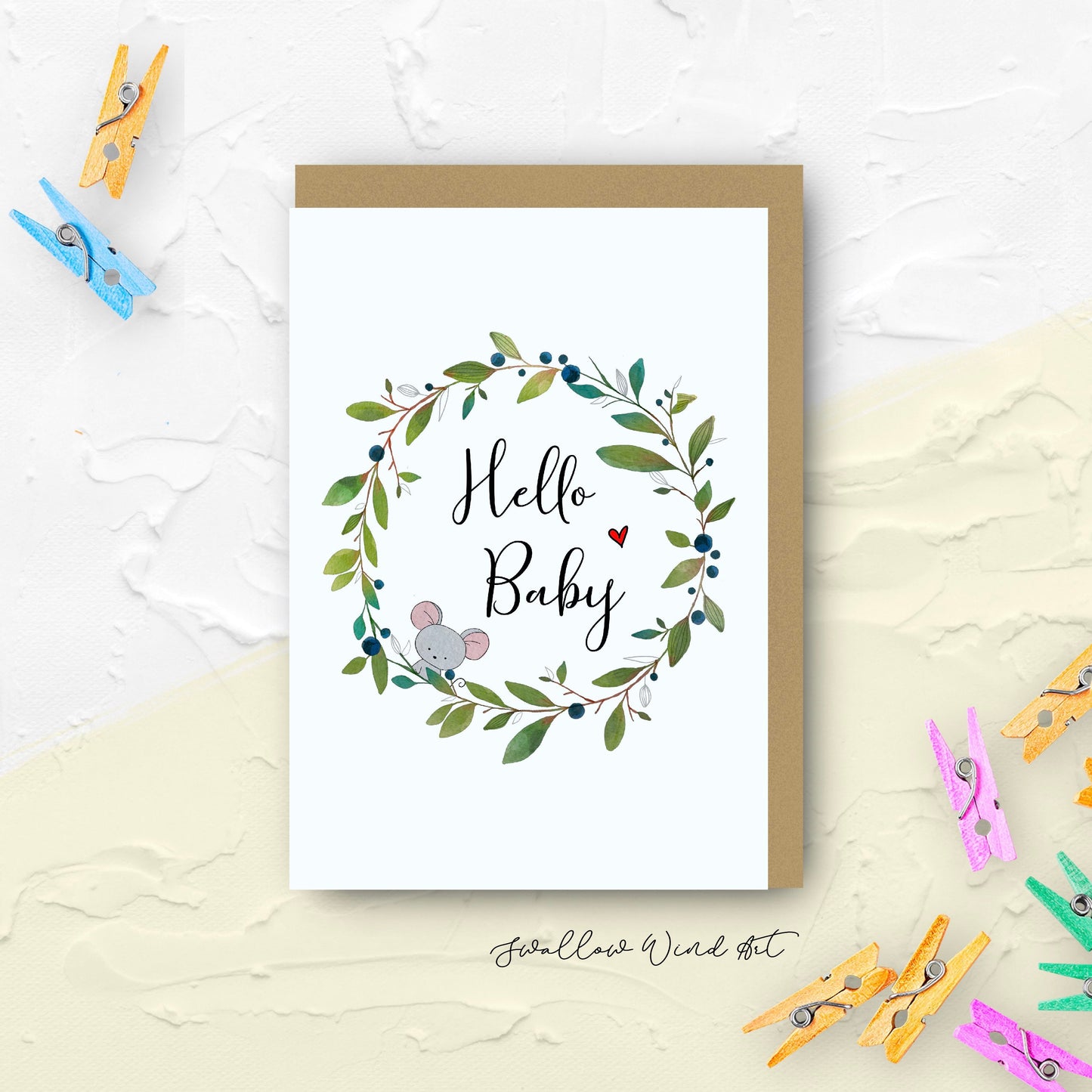 Greeting card with illustration of a wreath. Center of the wreath are the words "Hello Baby" with a little mouse peeping out and red love heart on either side